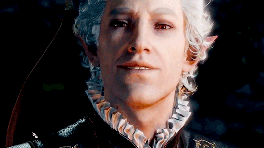 An elf with red eyes and white hair speaks in a sultry manner into the camera. Beneath his lips, sharp fangs can be briefly seen.