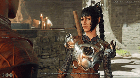 A raven-haired woman with pointy ears in intricately decorated chainmail speaks casually to someone just off-screen. Onl the listener's shoulder can be a seen. There are cobblestone walls in the background.
